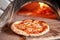 Baked tasty margherita pizza in Traditional wood oven in Naples restaurant, Italy. Original neapolitan pizza. Red hot