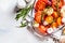 Baked tomatoes with garlic, onions and rosemary in glass oven dish, top view