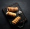 Baked tubules filled with whipped egg white cream on a black wooden kitchen board, top view