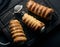 Baked tubules filled with whipped egg whites cream on a black wooden kitchen board