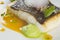 Baked turbot fillet on a white plate. Delicious fish meal with herbs and served with pea puree.