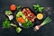 Baked veal shish kebab on a plate with fresh vegetables. On a wooden background. Top view.