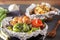 Baked vegetables in foil - tomatoes, eggplants, peppers and baked potatoes with bacon, onions on a gray wooden table.