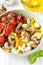 Baked vegetables with mushrooms in a bowl. Zucchini, cherry tomatoes on a branch, red onions, bell peppers and garlic. Delicious