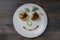 Baked yellow pepper, cucumber, green dill and french old-fashioned dijon mustard on a plate in the shape of a happy face, top view