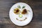 Baked yellow pepper, cucumber, green dill and french old-fashioned dijon mustard on a plate in the shape of a happy face, top view