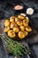 Baked youg potato with thyme in a pan Black background. Top view