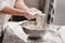 Baker adds flour to dough in an iron bowl on the table in the bakery