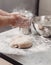 Baker adds flour to dough on the table in the bakery