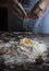 Baker breaking an egg into a flour mixture