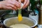 Baker breaks egg open over flour for the dough preparation