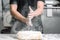 Baker claping hands with flour in restaurant kitchen.