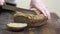 Baker cutting freshly baked loaf of homemade organic sourdough rye bread with bread knife