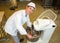 Baker with dough kneading machine in bakery