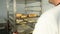 Baker filling oven in bakery, bakehouse. Man moves tray with loaves of fresh