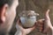 Baker hand holds glass jar with sourdough and make thumb up gesture, like sign, brown background, bread leaven starter