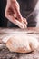 Baker hand sprinkle flour on fresh bun close-up