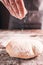 Baker hand sprinkling flour on fresh warm bread