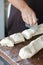 Baker hands at bakery house rolled buns with poppy seeds baking sheet pan wooden table with flour bread white