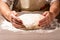 Baker hands making dough on wooden board in kitchen. Woman great-grandmother kneads dough for home baking