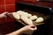 Baker hands with potholder taking out bread from oven