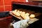 Baker hands with potholder taking out bread from oven