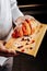 Baker holding wooden plate with croissant with sugar powder