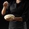 Baker keeps yeast dough on a black background with frozen flour in the air, bread, brioche, croissants, pizza, pasta. Concepts of