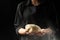 Baker keeps yeast dough on a black background with frozen flour in the air, bread, brioche, croissants, pizza, pasta. Concepts of