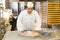 Baker kneading dough in bakery