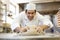 Baker kneading dough in bakery