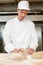 Baker kneading dough in bakery or bakehouse