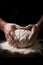 A baker kneads dough on a flour-dusted wooden table, hands covered in flour