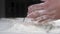 Baker man rubs wheat flour in his hands, and then claps his hands. Wheat flour flies dust over the table. Slow motion close-up.