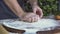 Baker pouring handful flour on wooden board and kneading dough on wooden table. Hand chef cook making dough for cake