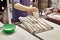 Baker pours flour on bread loaves before baking