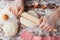 Baker prepares the dough on a wooden table, male hands knead the dough with flour