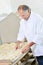 Baker preparing batch bread rolls