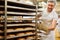 Baker pushes shelf trolley with ready-baked croissants