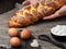 Baker puts easter braided bread on the table. Dark cloth background. Close-up, shallow depth of field.