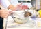 Baker sieving flour into a bowl in the kitchen of the bakery