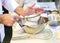 Baker sieving flour into a bowl in the kitchen of the bakery