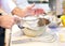 Baker sieving flour into a bowl in the kitchen of the bakery