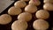 Baker sprinkles buns with sesame seeds.