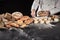 Baker sprinkling seeds or crushed wheat onto dough