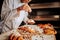 Baker standing near oven and decorating pastry desserts