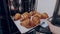 Baker takes freshly baked golden crispy classic croissants out of the oven. Bakery