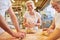 Baker team with apprentice kneading dough for baking