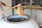 The Baker uses large wooden sticks to get the freshly baked tortillas out of the large clay oven. Unrecognizable person. Cooking