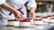 Baker Woman Artfully Decorating Cakes with White Kitchen Background - Close-up Shot.